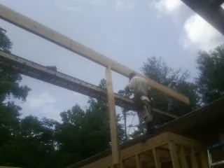 Carpenter setting a ridge beam over a new addition frame — Ice Dam Removal by Roofing Brothers in Garysburg