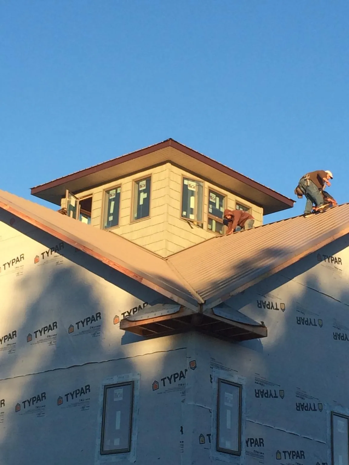 Roofers working around a rooftop cupola on a new metal roof at sunset — Roof Waterproofing in Garysburg by Roofing Brothers